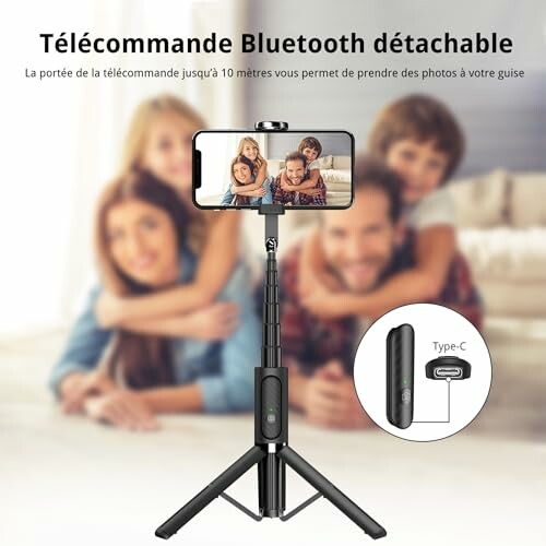 Selfie stick avec télécommande Bluetooth et famille souriante en arrière-plan.